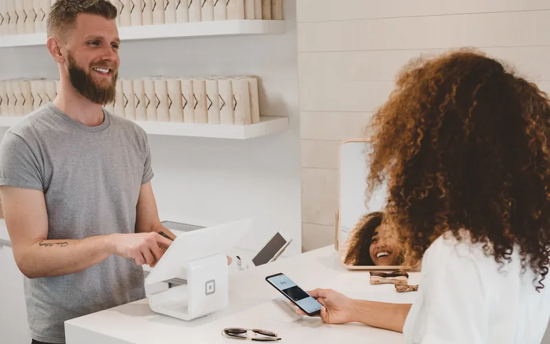 Stock photograph of a shop assistant handing a parcel to a customer at a counter