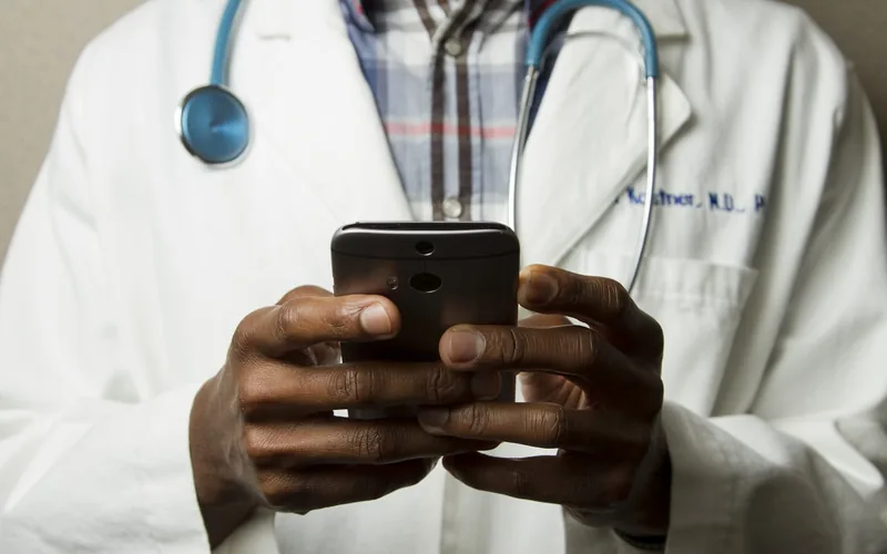 Stock photograph of a doctor in a white coat using a phone